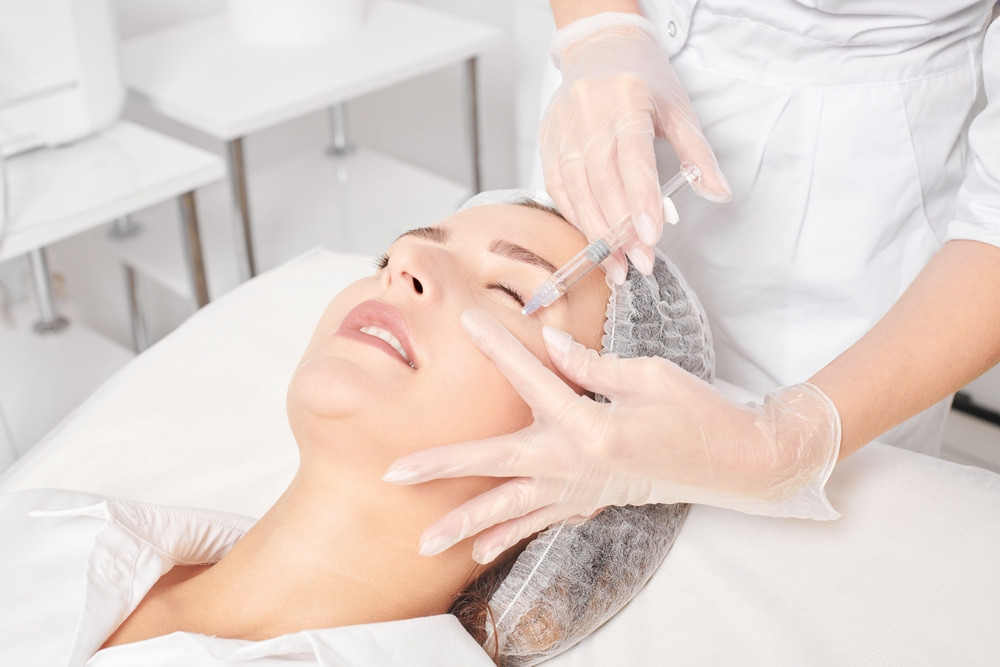 A woman receives a facial filler injection under her eye