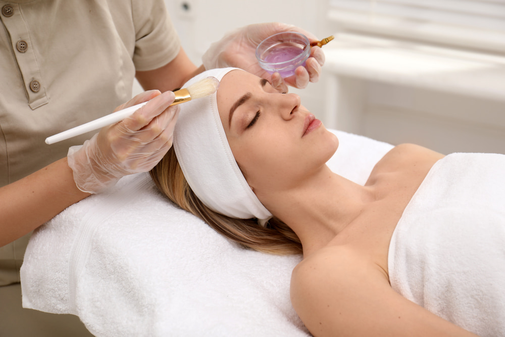 Aesthetician applying a chemical peel treatment to a client’s face to rejuvenate and enhance skin texture.