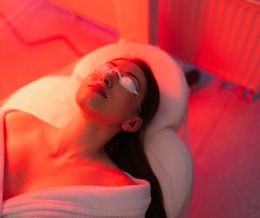 Patient undergoing photodynamic therapy (PDT) treatment under red light, wearing protective goggles in a clinical setting.